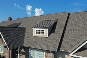 Asphalt shingle residential roofing on a house with a dormer window and rooftop vent.