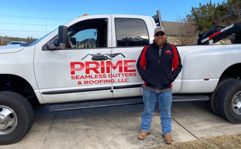 Man in red and black jacket standing in front of white Prime Seamless Gutters & Roofing truck in San Antonio, Texas