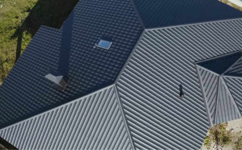 Aerial view of a house with metal roofing and dark shingle sections, showing roof installation and gutter systems in San Antonio